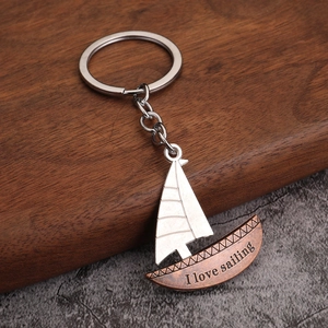 Porte-clés voilier en métal bicolore avec gravure I love sailing sur fond bois