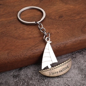Porte-clés voilier rétro en bronze avec gravure I Love Sailing sur fond de bois sombre