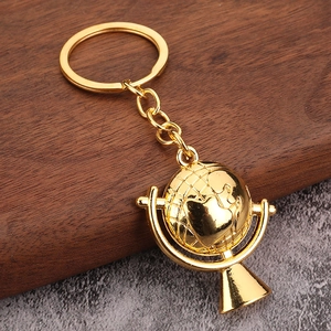 Golden spinning globe keychain with heart-shaped land contours on a wooden stand