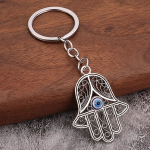Vintage silver Hamsa Hand keychain with Evil Eye pendant on wood and stone background