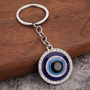 Close-up of blue evil eye owl keychain with sparkling rhinestones on wood base