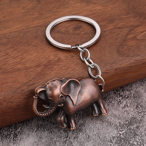 Vintage bronze elephant keychain with realistic animal details on dark wood surface