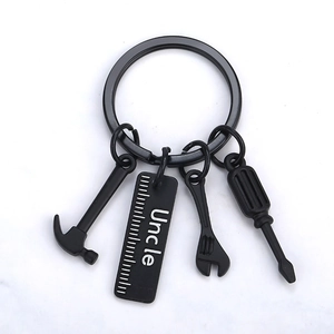Matte black metal tool keychain set with hammer, ruler, wrench and screwdriver on white base