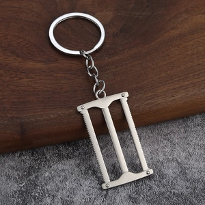 Macro view of realistic 3D mini hand saw keychain made of polished silver alloy