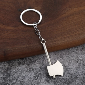 Close-up of a silver axe-shaped metal keychain on a wood and stone background