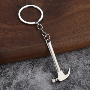 Close-up of claw hammer keychain made of matte silver alloy on a textured stone background