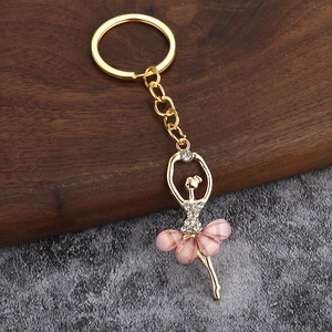 Pink crystal ballet dancer keychain with gold alloy frame on stone and wood background