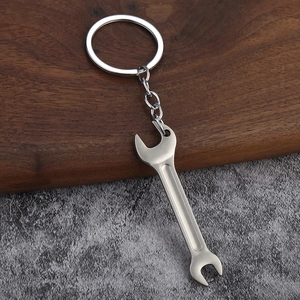 Macro shot of industrial metal wrench keychain with matte brushed finish on wood background