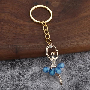 Macro shot of gold ballerina pendant with blue crystal skirt on a stone surface