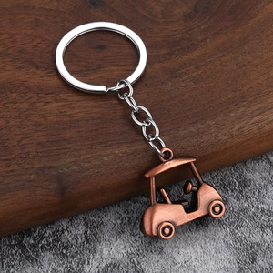 Detailed close-up of a bronze vintage style 3D golf cart keychain on stone background