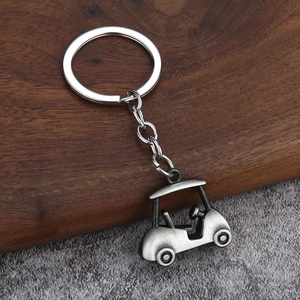 Macro detail of a 3D silver golf cart keychain with steering wheel on wooden background