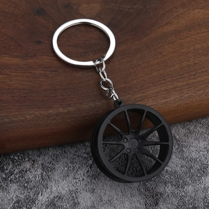 Detailed view of matte black 10-spoke car wheel rim keychain on stone background