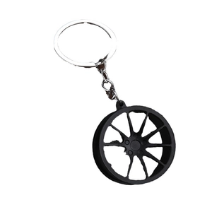 Matte black sporty car wheel rim keychain with silver metal chain on white background