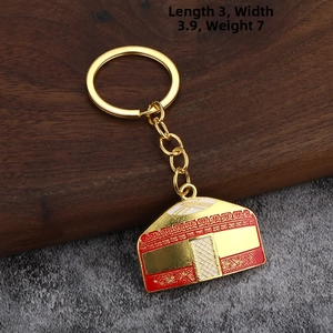 Detail of yurt-themed gold keychain with red and white enamel patterns, 3.9cm width
