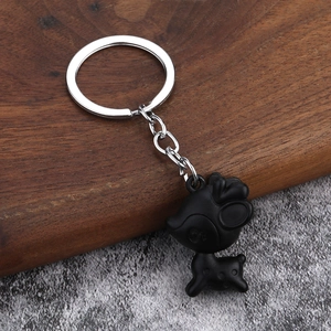 Cute matte black deer keychain with silver metal ring on a rustic wooden surface