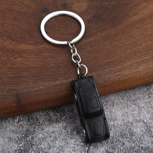 Detalle de llavero de coche vintage negro metálico con anillo en fondo de madera y piedra