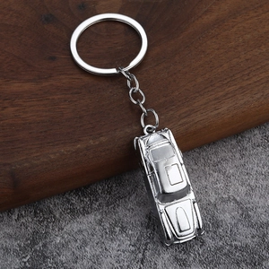 Detalle de un llavero de coche antiguo plateado sobre un fondo de madera rústica