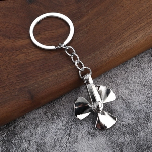 Rotating propeller metal keychain with polished silver finish on a wooden background