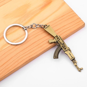 Vintage bronze alloy rifle gun keychain model on a wooden surface for PUBG game fans