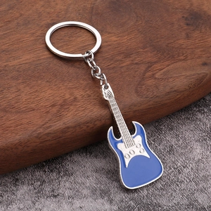 Detailed close-up of a blue and silver metal electric guitar keychain on a wooden surface