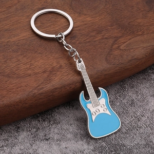 Detailed view of an electric guitar keychain with light blue lacquer on a stone surface