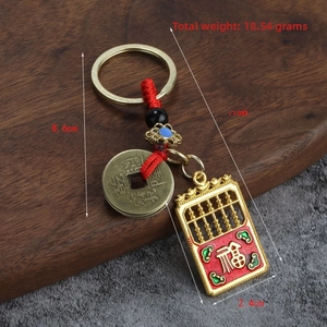 Détail du porte-clés en alliage avec mini boulier, pièce antique et corde rouge