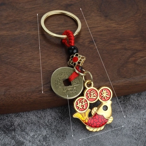 Détail du porte-clés carpe koi avec cordon rouge et pièce ancienne sur bois