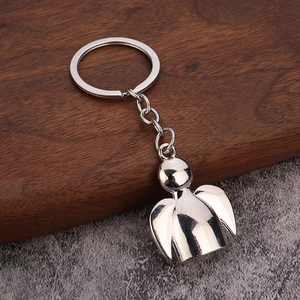 Polished silver metal angel keychain with wings on stone and wood surface background