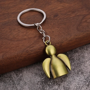 Detail of angel-shaped bronze keychain with matte finish on rustic stone surface