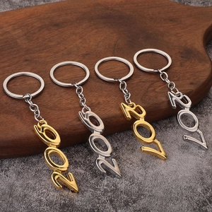 Golden and silver metal number 2021 keychains neatly arranged on a rustic wooden tray