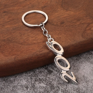 Polished silver metal 2021 number keychain on a rustic wooden and grey background