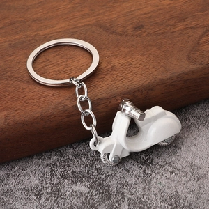 Macro shot of white alloy Vespa-style scooter keychain with silver ring on wooden base