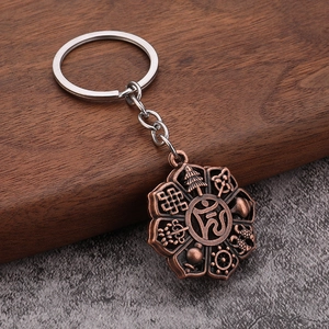 Detailed close-up of antique bronze Buddhist Om pendant on a polished metal keychain