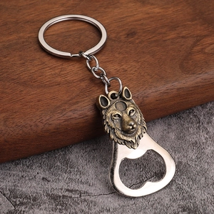 Detail of vintage wolf head embossed metal bottle opener keychain on a wooden surface