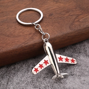 Polished silver metal airplane keychain with red stars on wings over wooden display