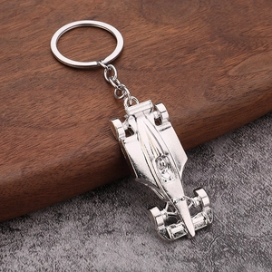 Polished silver zinc alloy F1 racing car keychain for men on a dark wood and stone surface