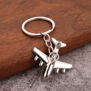 3D airplane model keychain in silver alloy with polished metal finish on wooden background