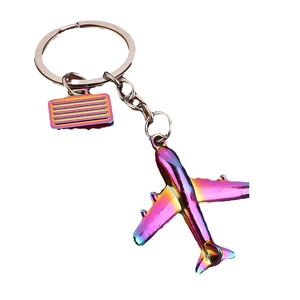 Rainbow metal airplane keychain with matching miniature suitcase pendant on white backdrop