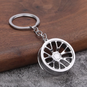 Polished silver metal car wheel rim keychain with a sporty multi-spoke design on stone base
