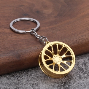 Detailed close-up of a golden alloy car wheel rim keychain on a wooden display stand
