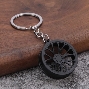 Macro shot of matte black automotive wheel rim keychain on natural wood background