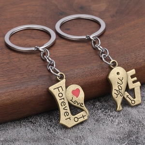 Romantic couple keychains set with heart charms and Forever Love engraving on dark wood