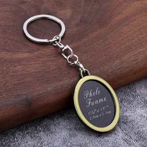Vintage oval metal photo frame keychain with silver ring on dark wooden background