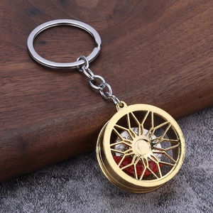 Macro detail of a 3D gold car wheel rim keychain with silver brake disc and red caliper