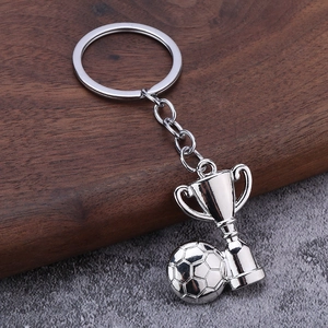 Polished silver metal soccer trophy keychain on a premium textured wood background
