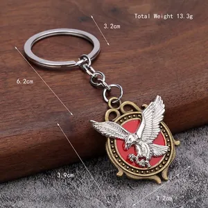 Eagle metal keychain with silver eagle relief and red enamel detail on wood background