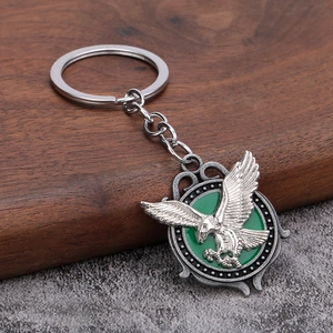 Retro eagle relief metal keychain with green enamel background on rustic wood surface