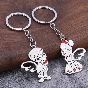 Polished silver couple keychains with red enamel details on dark wooden surface