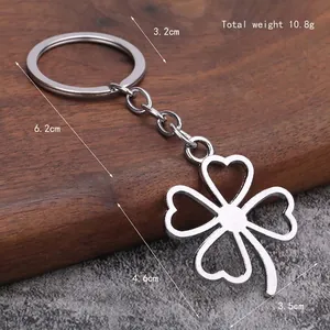 Minimalist silver clover keychain with heart-shaped leaves on stone and wood background