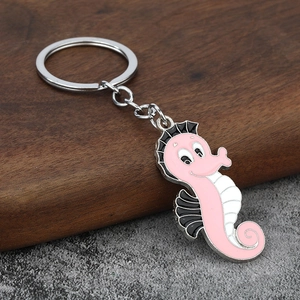 Porte-clés hippocampe rose en alliage de zinc et émail sur une surface en bois de noyer